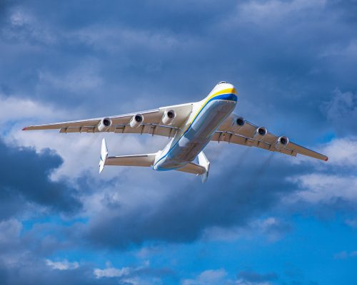 A large cargo plane flies in the blue sky. Aviation air transport. Airplane symbol.